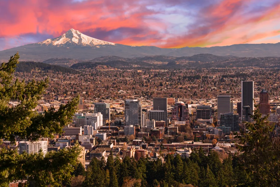 Sweeping view of Portland, Oregon with Mt. Hood in background against sunset sky.